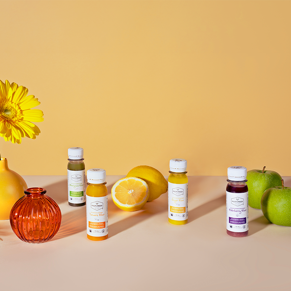 4 wellness shot elixirs ginger wellness shot turmeric wellness shot elderberry wellness shot and wheatgrass wellness shot on orange background 